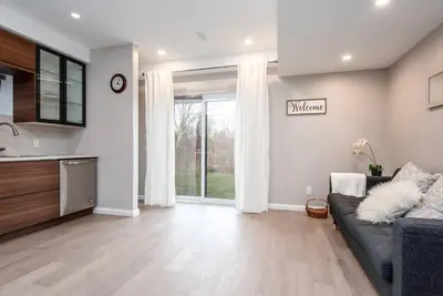 a living room with a couch and a kitchen at The Simple Escape, Walkout Basement on Ravine in Kitchener