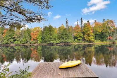 a yellow kayak sitting on a wooden dock on a lake at Muskoka Waterfront Cottage with Canoes and Fire Pit in Huntsville