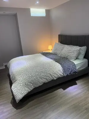 a bedroom with a bed with a black and white comforter at Beautiful&Spacious 2 Bedroom Basement Family Suite in Bradford