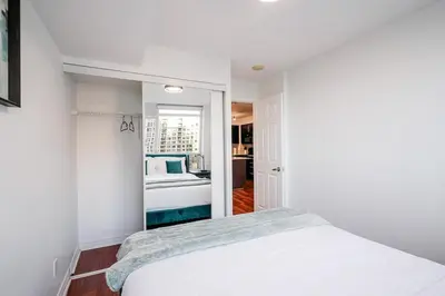a white bedroom with a bed and a mirror at Elegant 2BR 2BA Condo Heart of Mississauga SQ1 in Mississauga