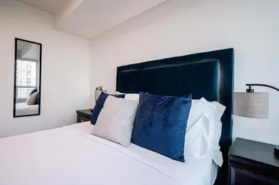 a bedroom with a white bed with blue pillows at Elegant 2BR 2BA Condo Heart of Mississauga SQ1 in Mississauga