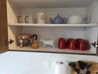 a shelf with cups and tea pots on it at Cozy Home for 10 people in Kitchener