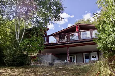 a house with a wrap around deck with trees at Serendipity 5 BR Waterfront 4 Seasons, Hot Tub, Firepit, Close to Ski HIll in Haliburton