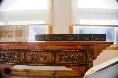 a wooden table with a welcome to the lake sign on it at Serendipity 5 BR Waterfront 4 Seasons, Hot Tub, Firepit, Close to Ski HIll in Haliburton