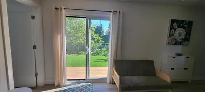 a living room with a sliding glass door to a yard at Bright Garden Suite 1 Bedroom and Den in Toronto