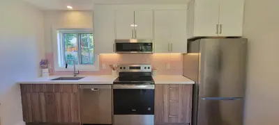 a kitchen with a stainless steel refrigerator and a sink at Bright Garden Suite 1 Bedroom and Den in Toronto