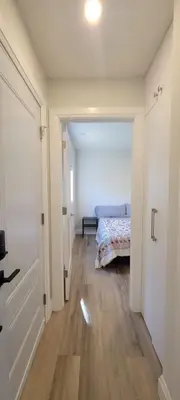 a hallway with a bed in a white room at Bright Garden Suite 1 Bedroom and Den in Toronto