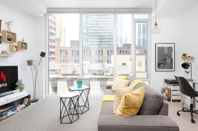 a living room with a couch and a large window at Chic 1BR King Suite TOs Entertainment District in Toronto
