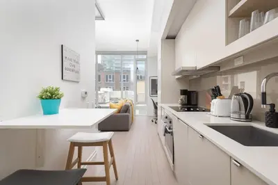 a white kitchen with a sink and a counter at Chic 1BR King Suite TOs Entertainment District in Toronto