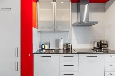 a kitchen with white cabinets and a red wall at Fort York Studio a Cozy Retreat in Downtown in Toronto
