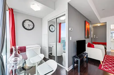 a living room with a clock on the wall at Fort York Studio a Cozy Retreat in Downtown in Toronto