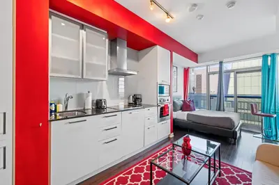 a kitchen with white cabinets and a red wall at Fort York Studio a Cozy Retreat in Downtown in Toronto