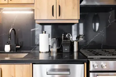 a kitchen with a stove and a black counter top at Modern Parkdale Getaway 1-Bedroom Parking in Toronto
