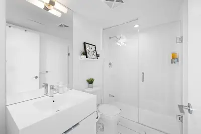 a white bathroom with a sink and a shower at Modern Lakefront Esc Stylish 2BR Condo with Patio in Toronto