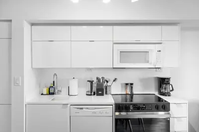 a white kitchen with a stove and a microwave at Modern Lakefront Esc Stylish 2BR Condo with Patio in Toronto