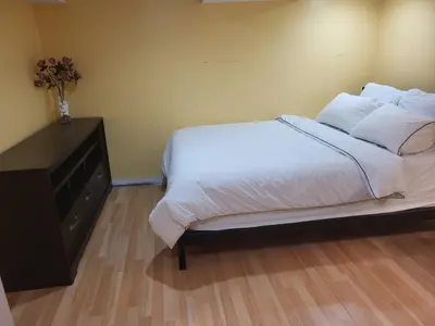 a bedroom with a bed with white sheets and a dresser at 75 inch high mud house with separate entrance and exit, one bedroom, one living room, private bathroom, there is a cute cat, a few minutes walk to many restaurants, 8 minutes drive to the big waterfall in Niagara Falls