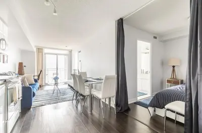 a living room with a dining room table and a bedroom at Spacious 1 Bedroom plus Den Condo Iceboat Terrace Downtown Toronto in Toronto