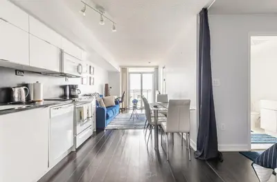 a kitchen with white cabinets and a table with chairs at Spacious 1 Bedroom plus Den Condo Iceboat Terrace Downtown Toronto in Toronto