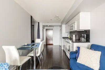 a kitchen and living room with a blue couch at Spacious 1 Bedroom plus Den Condo Iceboat Terrace Downtown Toronto in Toronto