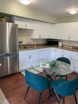 a kitchen with a glass table and white cabinets at Peterborough Cosy Apartment in Peterborough