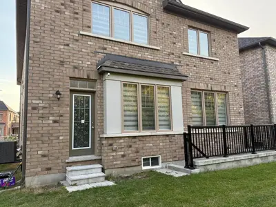a brick house with a black fence in the yard at Comfy Basement Suite in Quiet Neighbourhood in Whitby