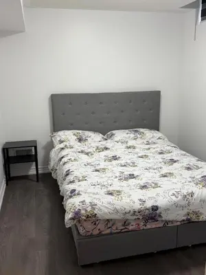 a bed in a bedroom with a bedspread on it at Comfy Basement Suite in Quiet Neighbourhood in Whitby