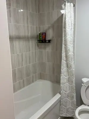 a bathroom with a bath tub and a toilet at Comfy Basement Suite in Quiet Neighbourhood in Whitby