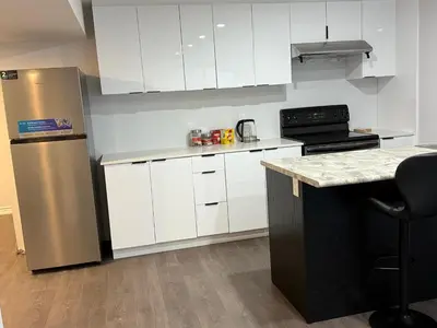 a kitchen with white cabinets and a stainless steel refrigerator at Comfy Basement Suite in Quiet Neighbourhood in Whitby