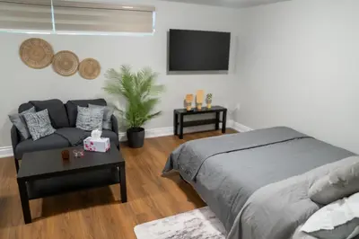 a bedroom with a bed and a couch and a tv at Studio Apartment B - Full Kitchen - Cozy and Modern in Brampton