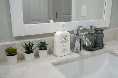a bathroom sink with a bottle of soap and a mirror at Studio Apartment B - Full Kitchen - Cozy and Modern in Brampton