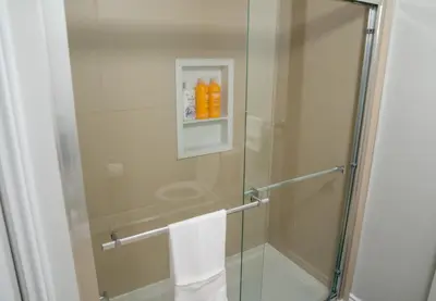 a shower with a glass door with orange bottles in it at Studio Apartment B - Full Kitchen - Cozy and Modern in Brampton