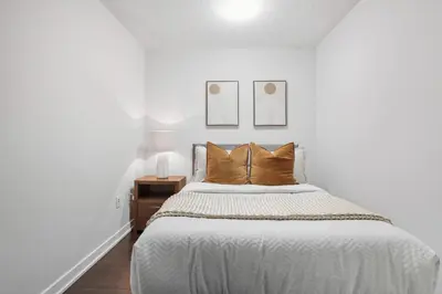 a white bedroom with a large bed with brown pillows at Trendy 1BR Condo Free Parking Downtown Toronto in Toronto