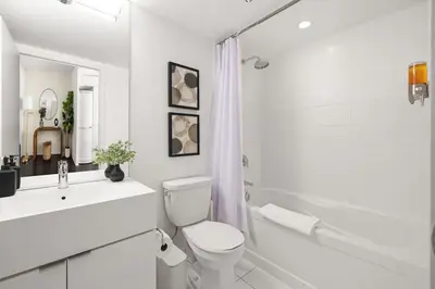 a white bathroom with a toilet and a sink and a shower at Stylish 1BR Condo with Patio Steps from Waterfront in Toronto