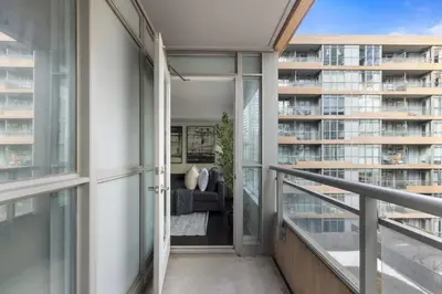 a balcony with a couch in front of a building at Stylish 1BR Condo with Patio Steps from Waterfront in Toronto