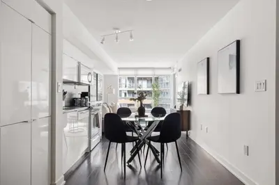 a kitchen and dining room with a table and chairs at Stylish 1BR Condo with Patio Steps from Waterfront in Toronto