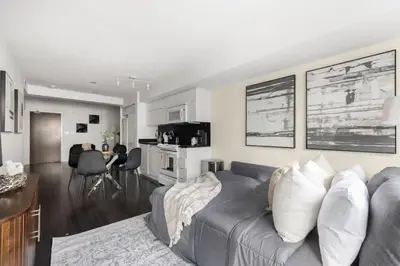 a living room with a gray couch and a kitchen at Stylish 1BR Condo with Patio Steps from Waterfront in Toronto