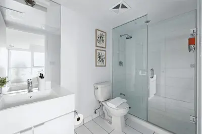 a white bathroom with a toilet and a shower at Modern 2BR Condo Stunning Views Walk Everywhere in Toronto