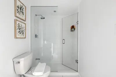a white bathroom with a shower and a toilet at Modern 2BR Condo Stunning Views Walk Everywhere in Toronto