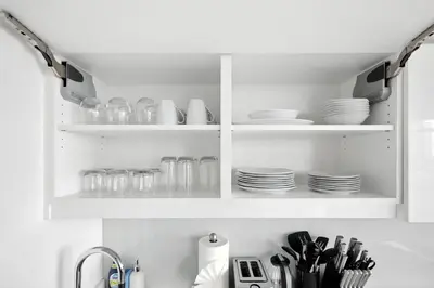 a kitchen with white cabinets with plates and dishes at Family-Friendly Sleep 8 Steps to all Attractions in Toronto