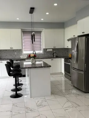 a kitchen with white cabinets and stainless steel appliances at masters bet room in Whitby