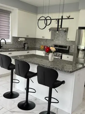 a kitchen with a counter with four bar stools at masters bet room in Whitby