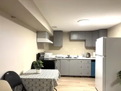 a small kitchen with a table and a refrigerator at Spacious 2-BR Basement Suite Near Lake Simcoe & Beach Park in Innisfil