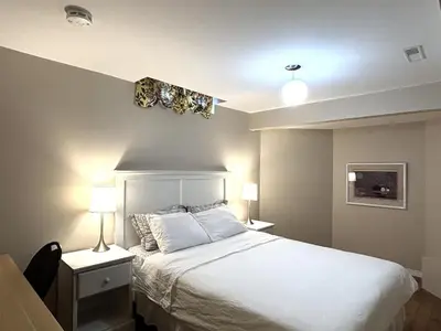 a bedroom with a large white bed with two lamps at Spacious 2-BR Basement Suite Near Lake Simcoe & Beach Park in Innisfil