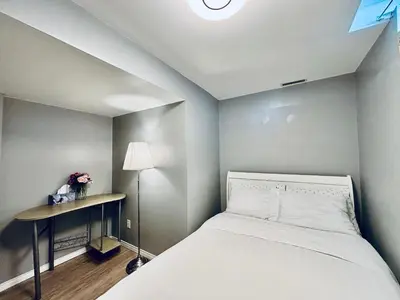 a small bedroom with a bed and a table at Spacious 2-BR Basement Suite Near Lake Simcoe & Beach Park in Innisfil