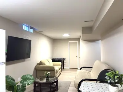 a living room with two chairs and a flat screen tv at Spacious 2-BR Basement Suite Near Lake Simcoe & Beach Park in Innisfil