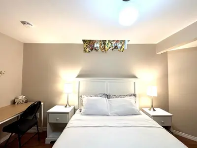a bedroom with a bed with a desk and two lamps at Spacious 2-BR Basement Suite Near Lake Simcoe & Beach Park in Innisfil