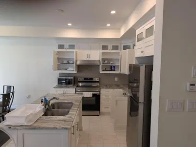 a kitchen with white cabinets and a stainless steel refrigerator at Modern 3BR Home Near Niagara Falls & Welland Canal in Welland
