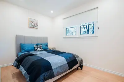 a bedroom with a bed and two windows at Bright, Modern & Cozy Getaway Home in the GTA in Whitby