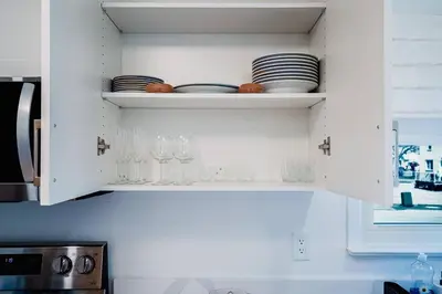 a kitchen with white cabinets with glasses and plates at Bright, Modern & Cozy Getaway Home in the GTA in Whitby
