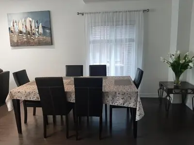 a dining room table with chairs and a table and a painting at Modern 5-bedroom house close to Ardagh Bluffs in Barrie